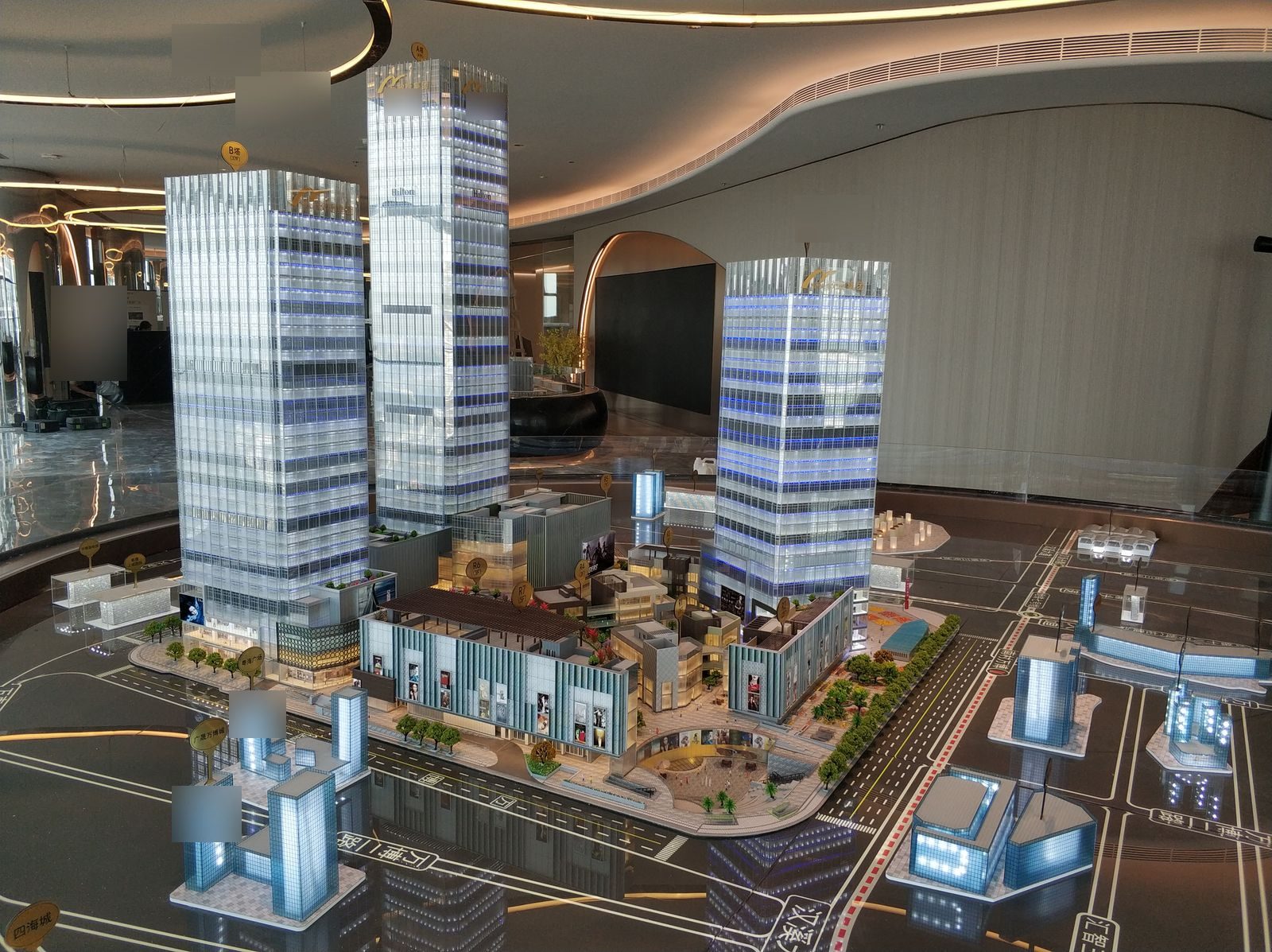 Mixed-use development model with three lit towers, retail podium and surrounding street network