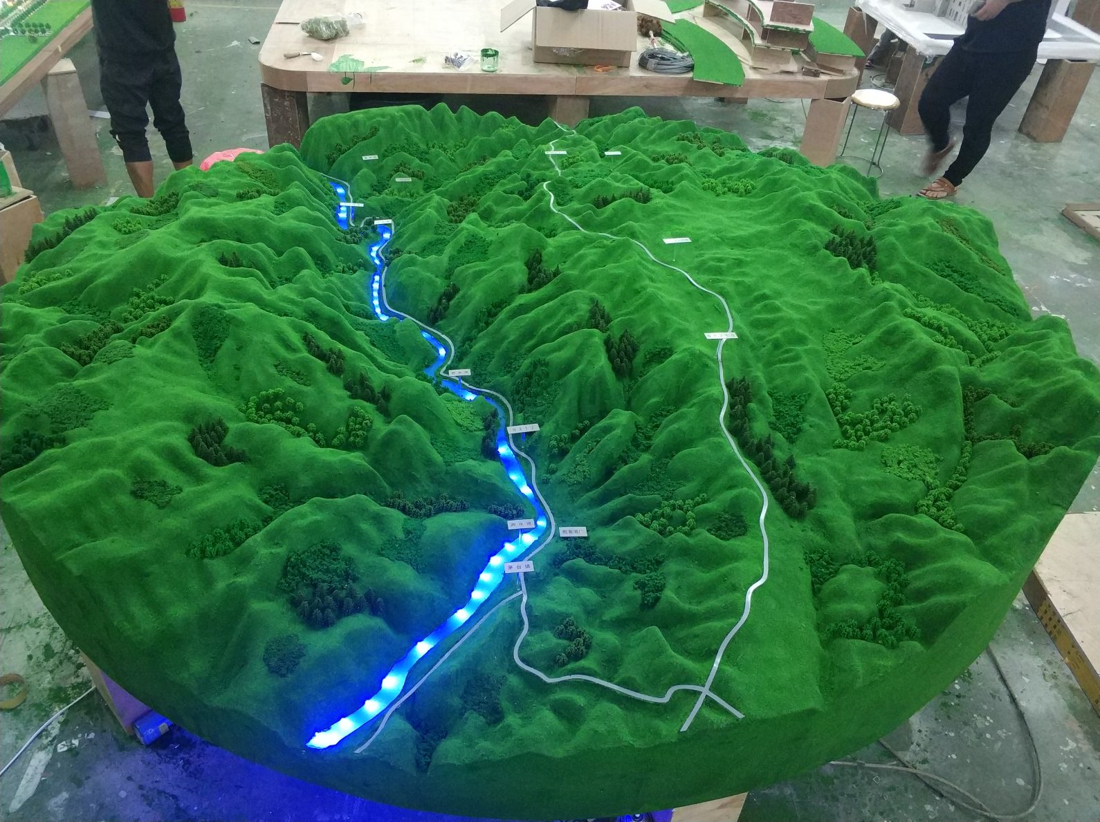 Topographic terrain model with routed lighting paths on an exhibition table